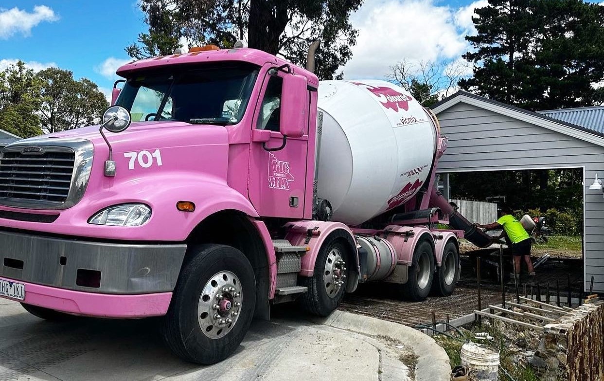 Vicmix pink truck on a home construction site.