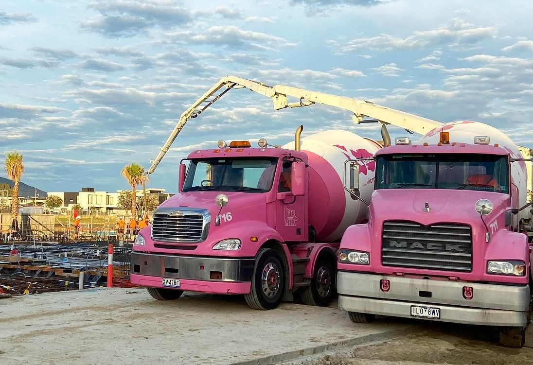 Two Vicmix pink concrete trucks at a construction site.