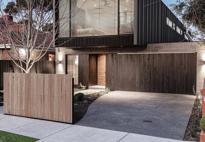 A modern home with a concrete driveway and wooden fence.