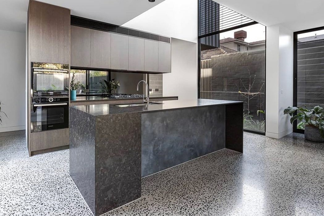 kitchen with a coloured aggregate concrete floor and a dark concrete island